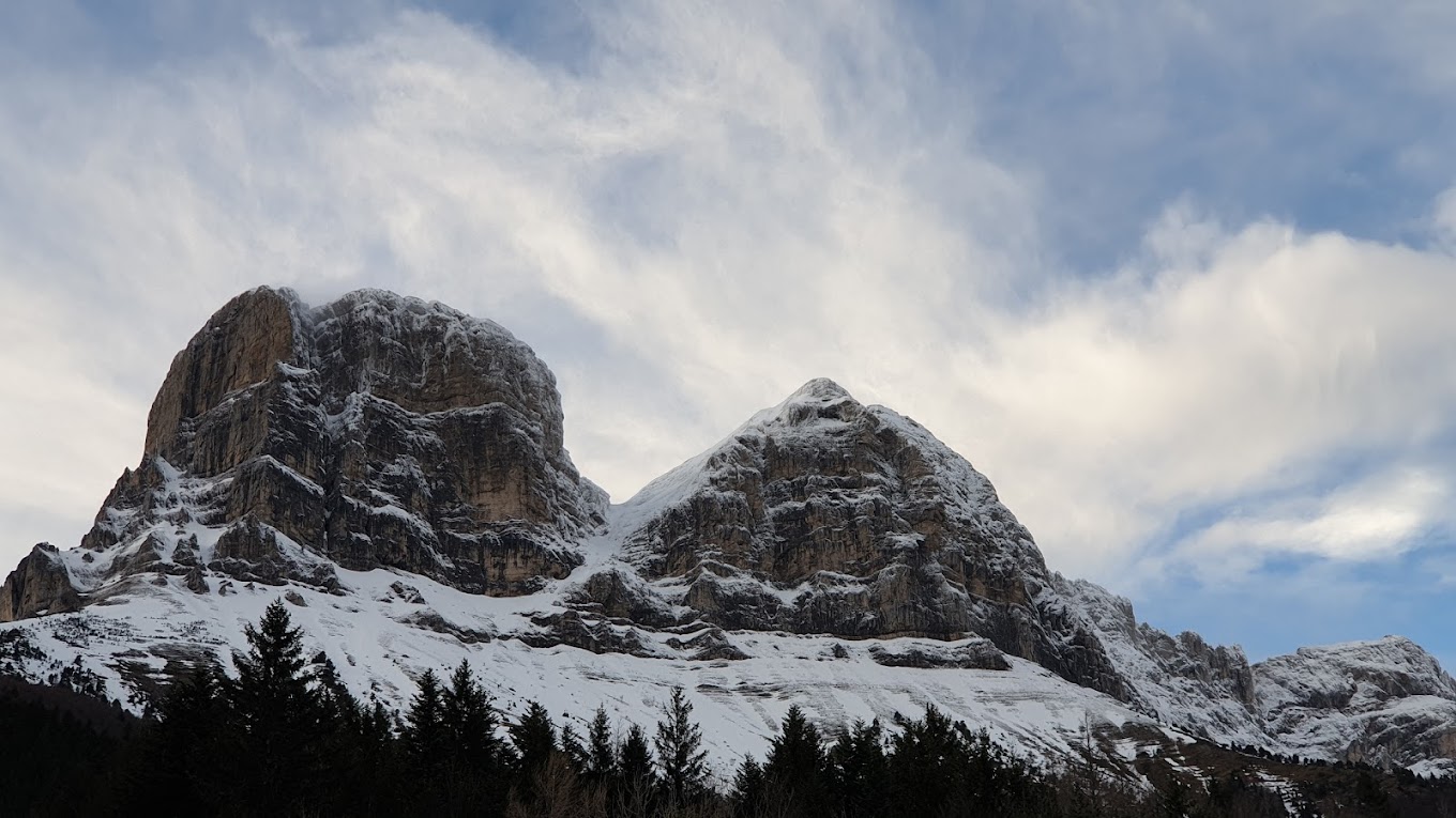 Col de l'Arzelier in France - a snow covered mountain with trees in the fore.