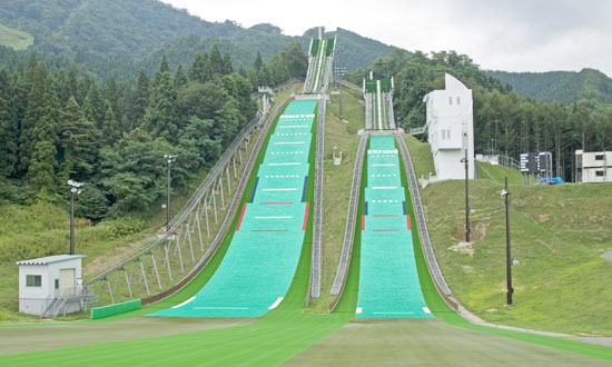 Hanawa in Japan - a ski slope with green grass on the side.