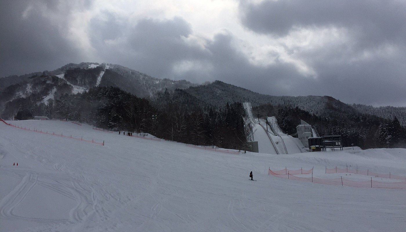 Hanawa in Japan - a person skiing down a hill on a cloudy day.