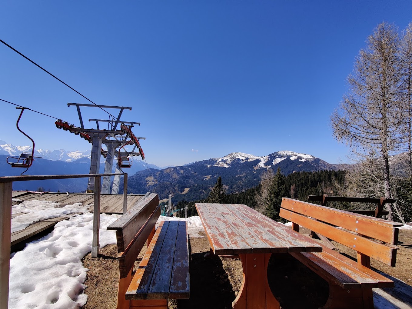 Španov vrh in Slovenia - a wooden bench with a ski lift in the background.