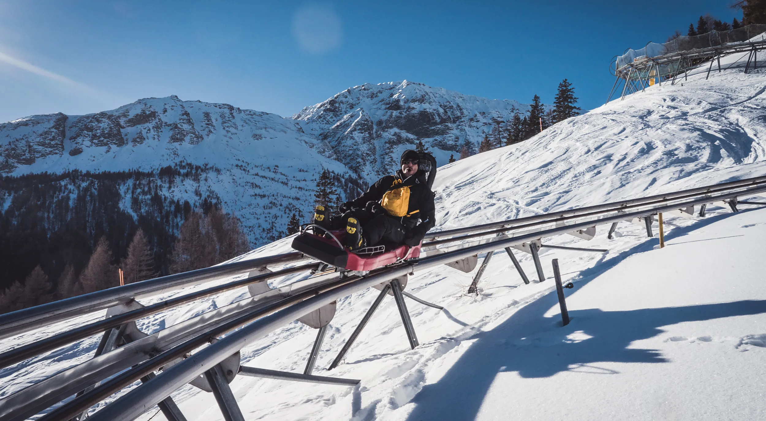 Sciovie Baita Valbella in Italy - a man riding a snowboard down a snow covered slope.