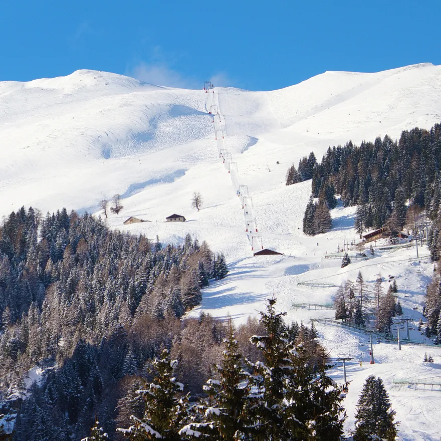 Sciovie Baita Valbella in Italy - a snow covered mountain with a ski lift in the background.