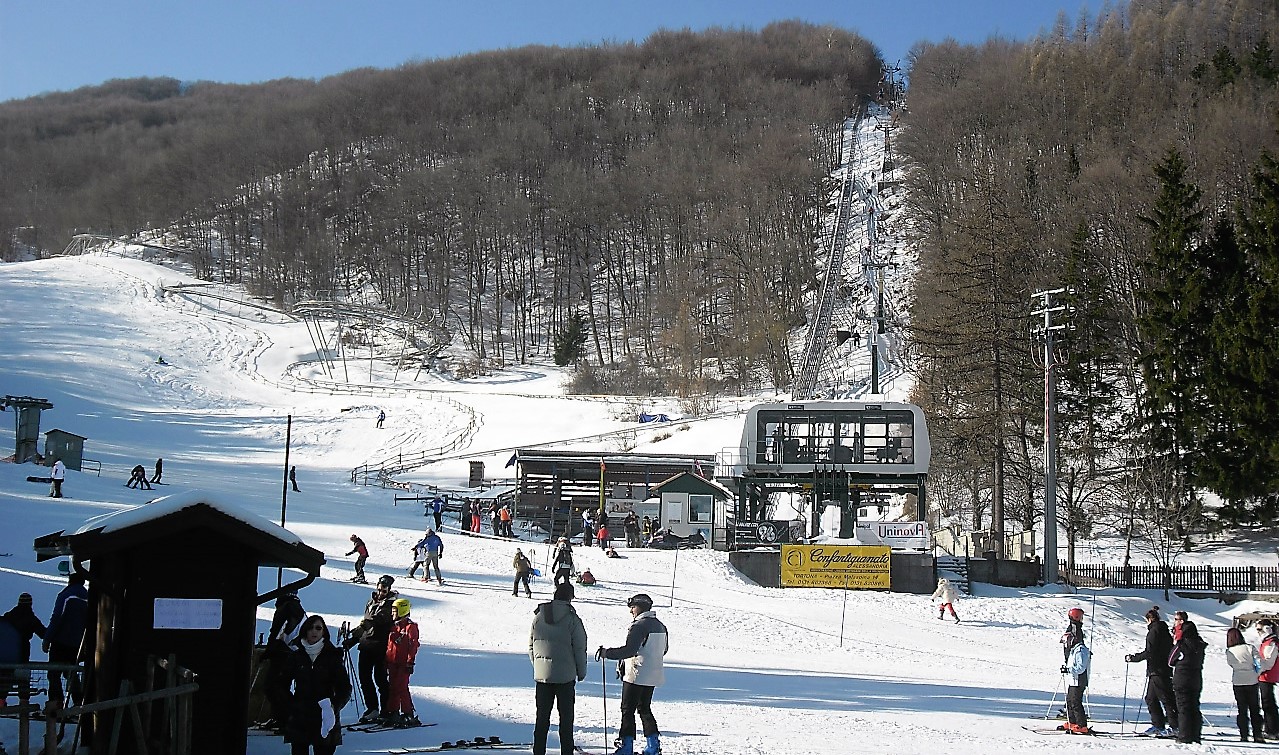 Seggiovia di Caldirola in Italy - a group of people skiing down a snowy slope.