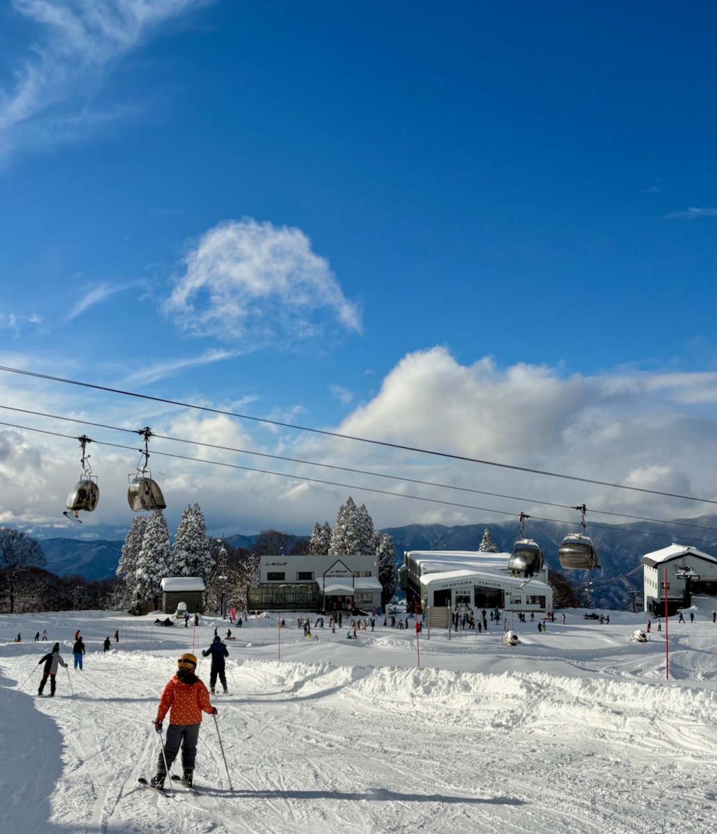 Nozawaonsen Nagasaka Gondola Yamabiko Sta. in Japan - a group of people skiing down a snow covered slope.