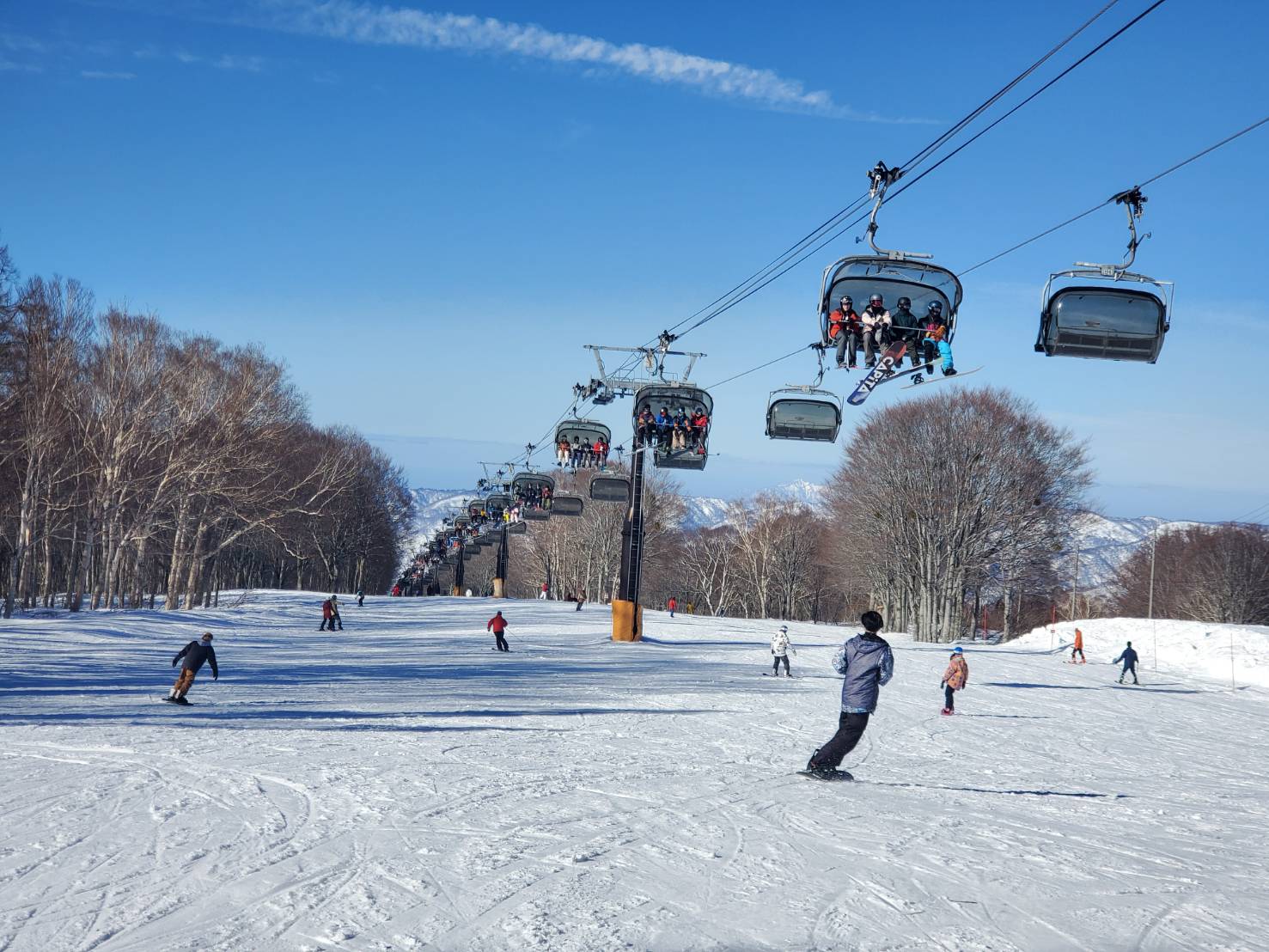 Nozawaonsen Nagasaka Gondola Yamabiko Sta. in Japan - a group of people skiing down a ski slope.