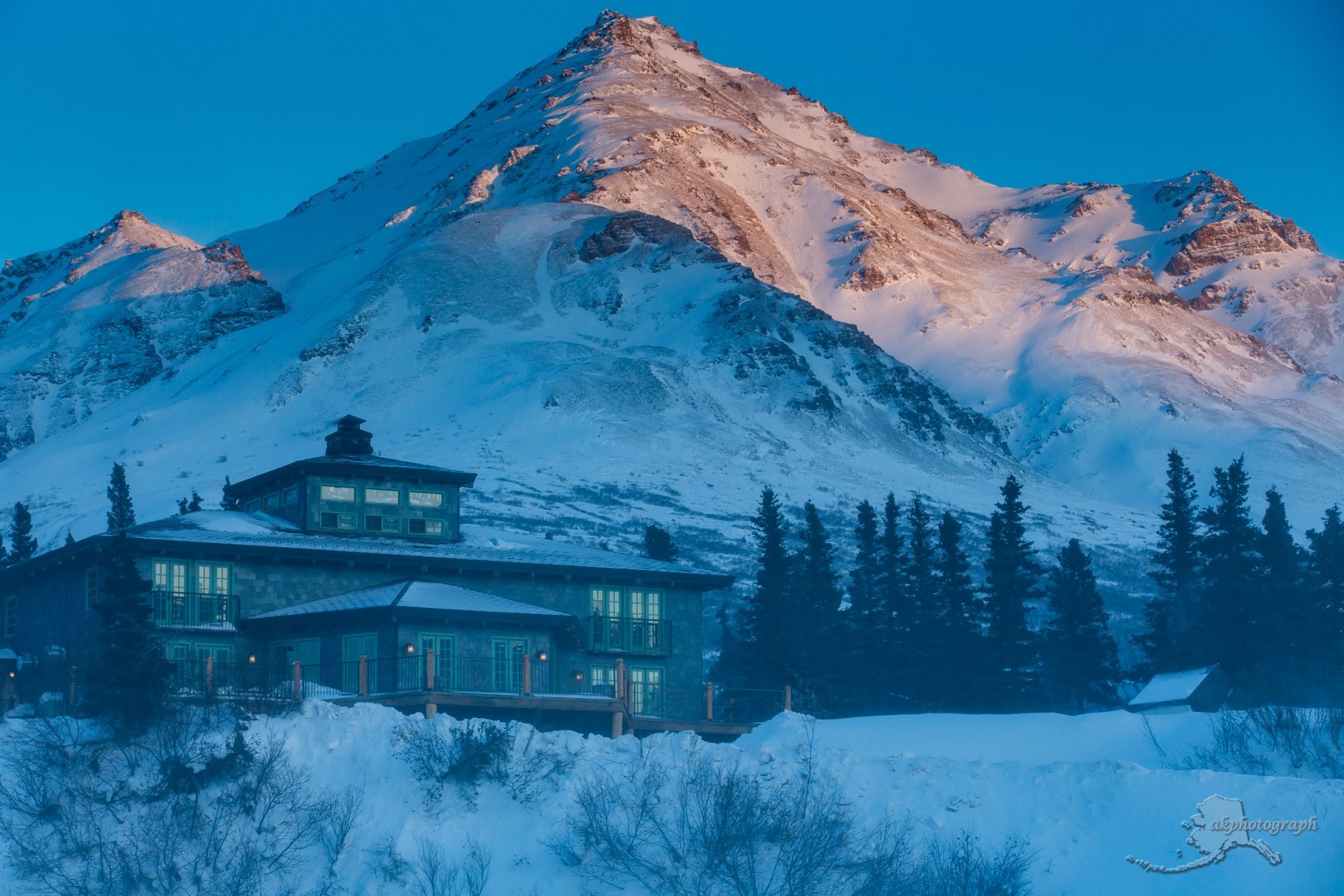 Spectacular winter scenery at Black Rapid, Alaska, featuring a lively ski resort with a cozy lodge nestled in picturesque snow-laden mountains.