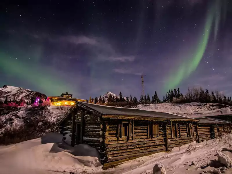 A beautiful winter sports scene at Black Rapid, Alaska, showcasing a bustling ski resort nestled amidst striking winter scenery. A cozy lodge provides a warm contrast to the icy backdrop.