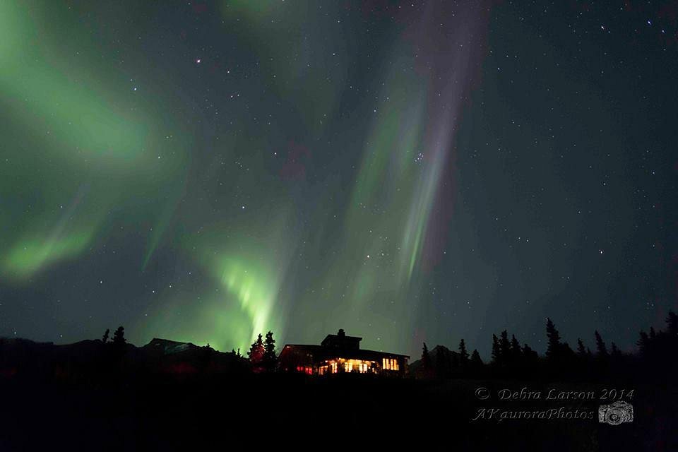 Image showcasing a rustic challet and lodge nestled in the snowy landscapes of Black Rapid, Alaska. Majestic mountains preside in the background, contributing to the atmosphere of this serene ski resort.