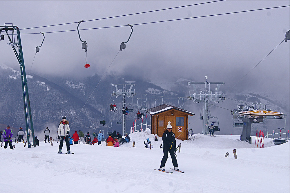Monte Prata Ski in Italy - a group of people skiing down a snowy hill.