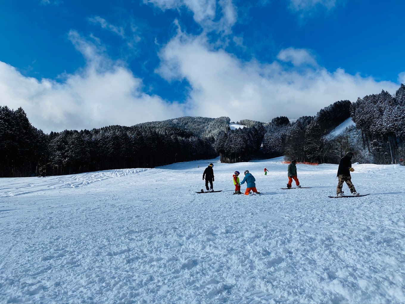 Kenmin-no-mori in Japan - a group of people riding snowboards on a snowy slope.