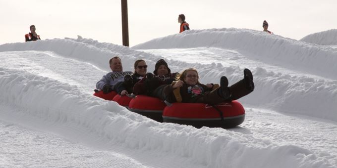 A winter scene at Wilmot Mountain Wisconsin with a snowmobile in the foreground. This popular ski resort also includes a chalet and various winter sports activities.