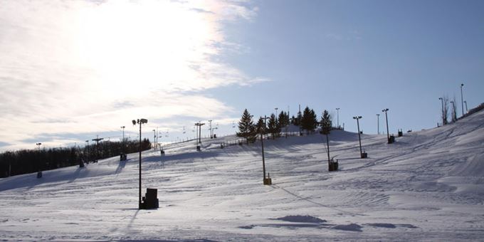 Winter scene at Wilmot Mountain ski resort in Wisconsin, featuring skiers on slopes, with ski lifts in the background and a chalet visible in the distance.