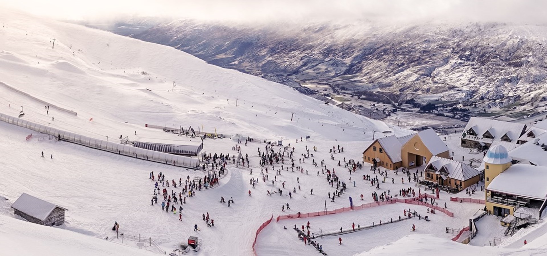 Cardrona in New Zealand - a group of people skiing down a snow covered mountain.