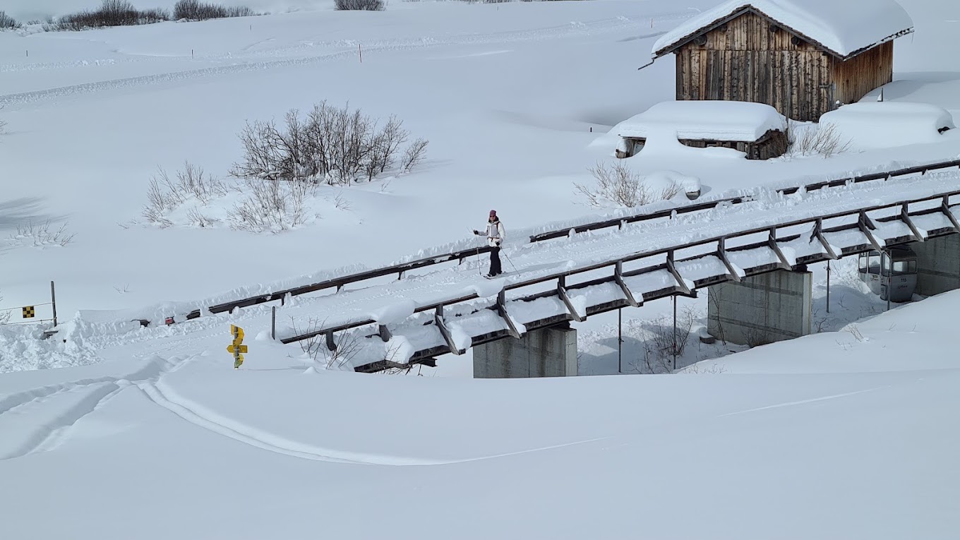 Avers in Switzerland - a man walking across a snow covered bridge.