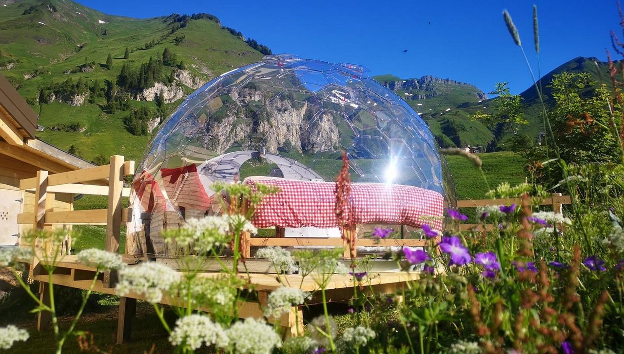 Gitschenen in Switzerland - a person sitting on a bed in front of a mountain.
