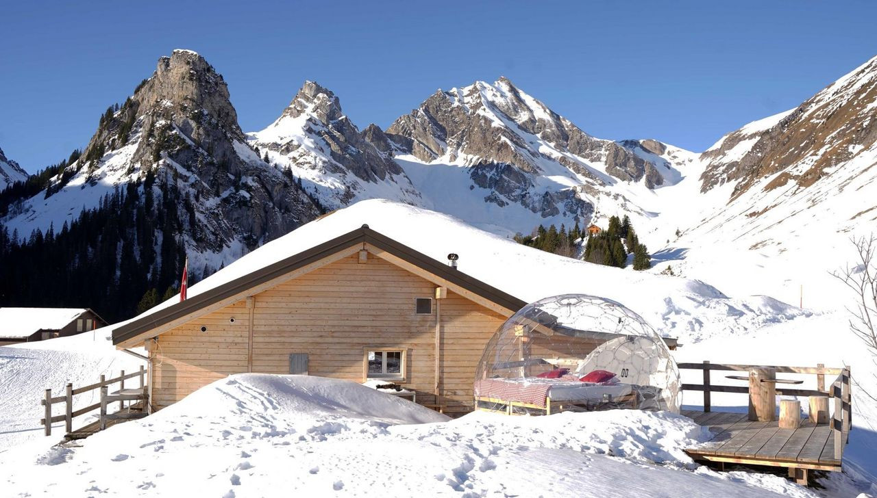 Gitschenen in Switzerland - a snow covered cabin with mountains in the background.