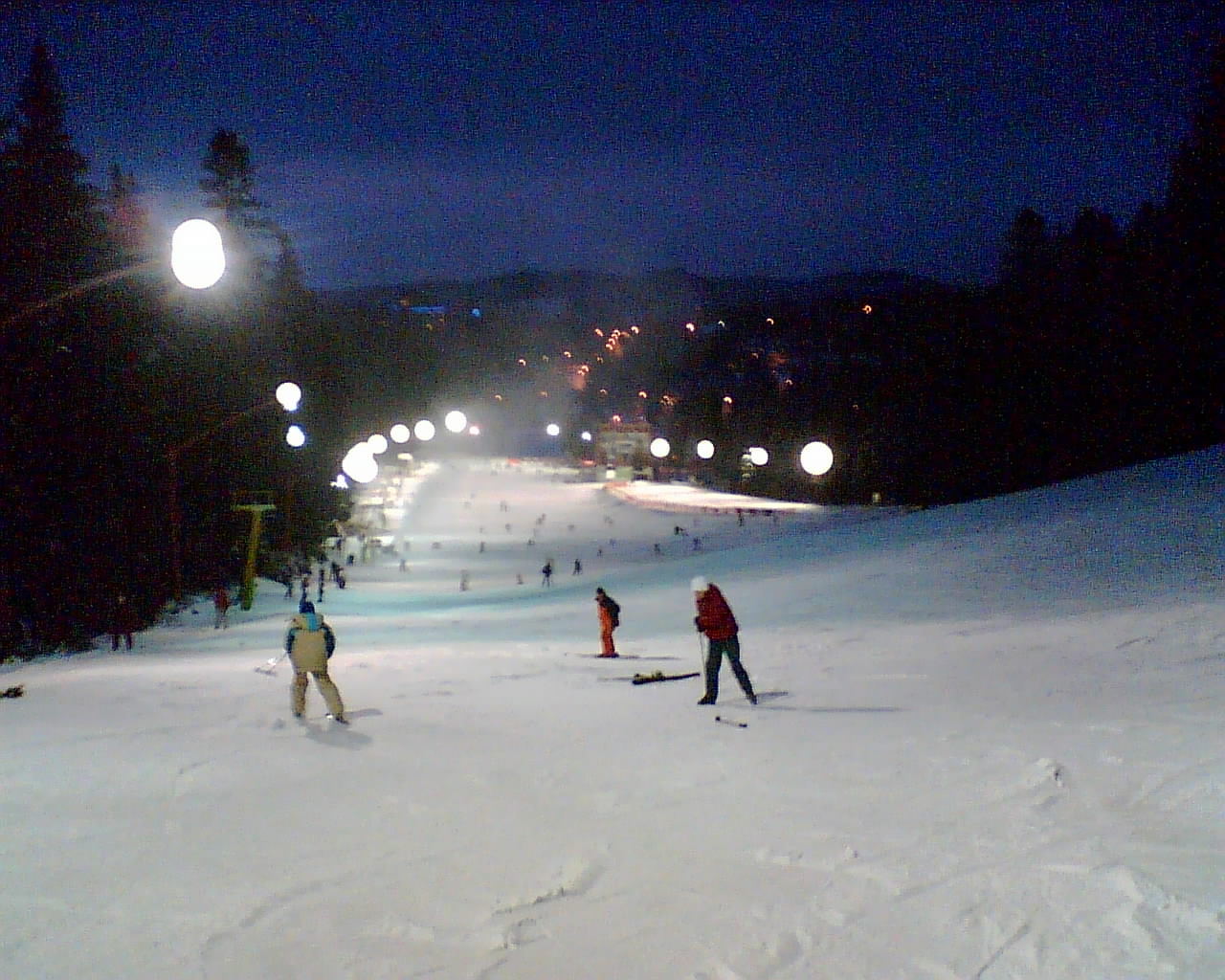 Buscat Ski & Summer Resort in Romania - a group of people skiing down a hill at night.