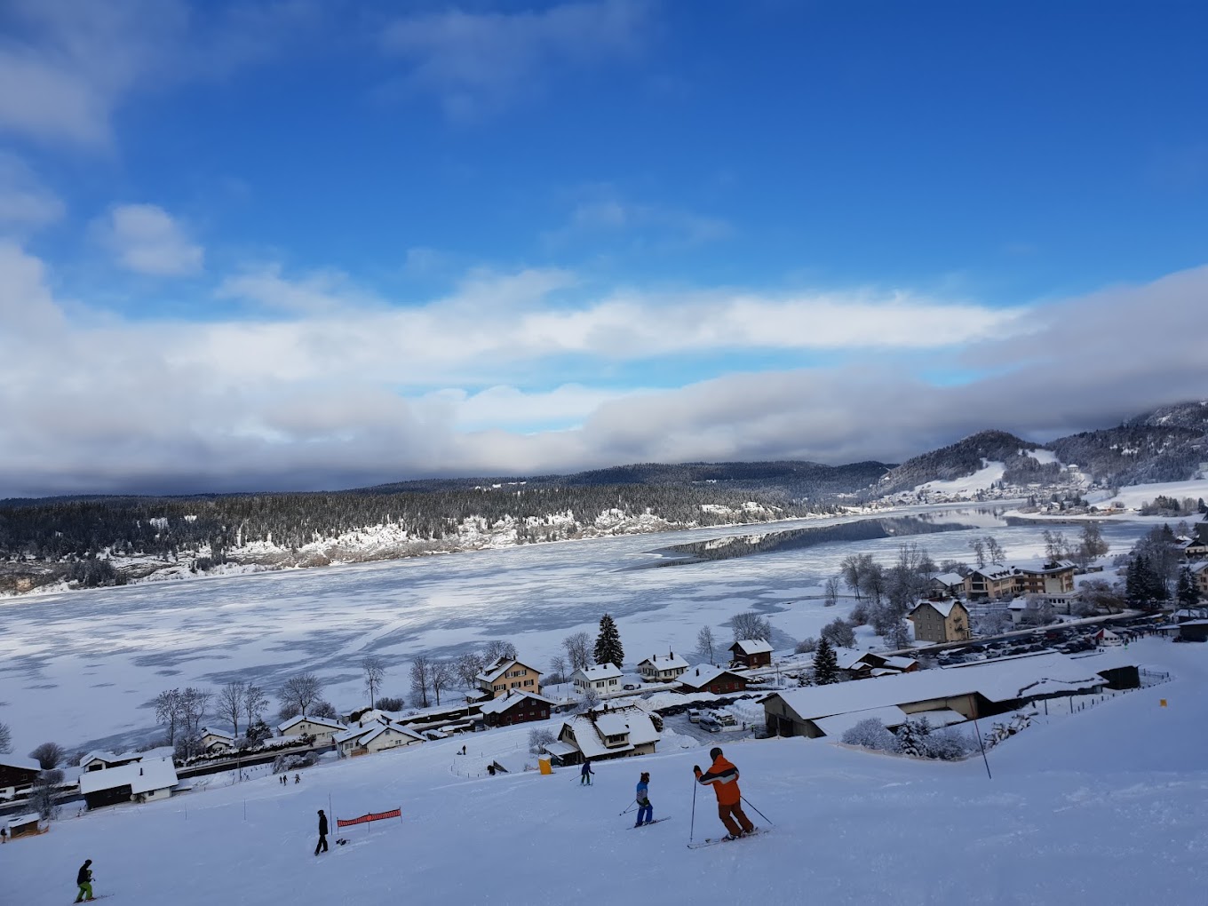 Lac de Joux in Switzerland - a group of people skiing down a snowy hill.