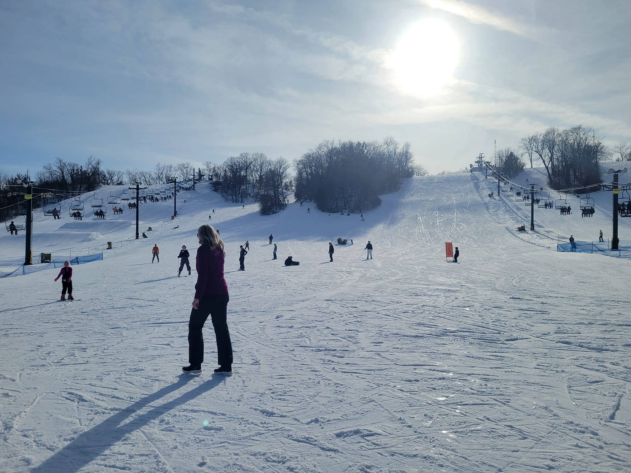 A winter sports scene at Seven Oaks, Iowa USA, featuring a ski resort with a charming chalet, and a solitary skier in action amidst the frosted landscape of the winter sports centre.