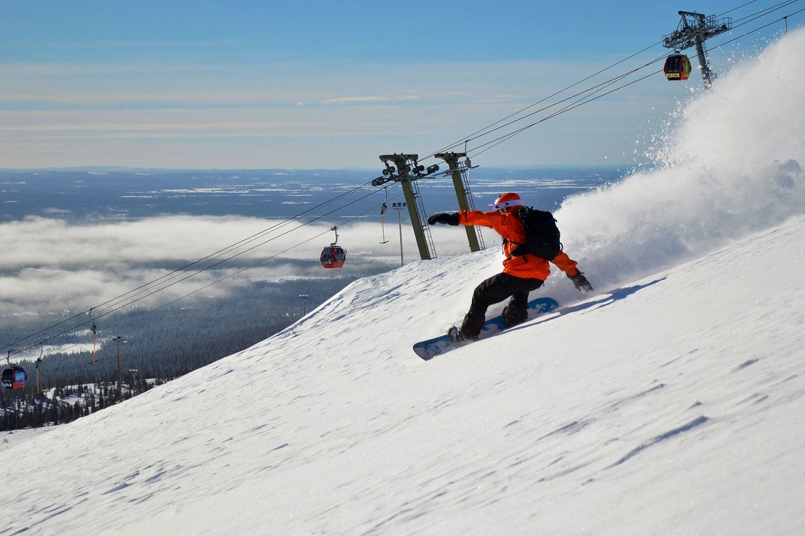 Ylläs in Finland - a man riding a snowboard down a snow covered slope.