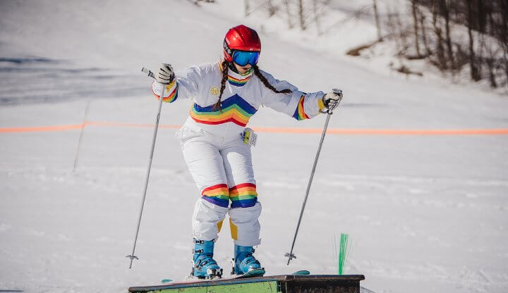 Shanty Creek Summit Mountain in USA - a woman in white ski suit and red helmet skiing down a slope.