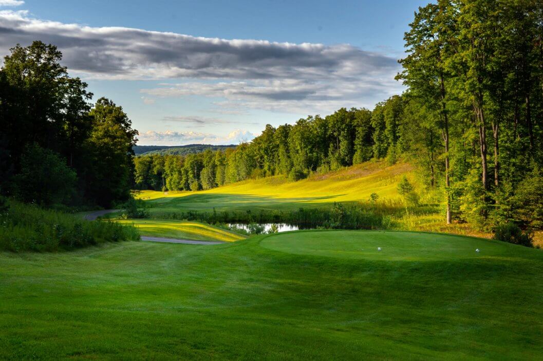 A sunny day at Shanty Creek Resorts – Summit Mountain Michigan showcasing a grand challet amidst a forest of trees with a hint of winter sports activities near a cozy lodge.