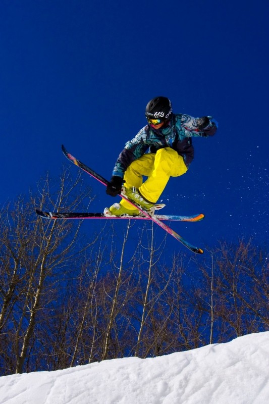 A skier and a snowboarder enjoy the snowy slopes at Shanty Creek Resorts' Summit Mountain, Michigan, with a quaint chalet in the background.