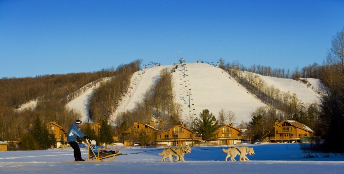 Ski lift operating at the snow-covered Shanty Creek Resorts – Summit Mountain, Michigan. Skiers are enjoying various winter sports on the slopes.