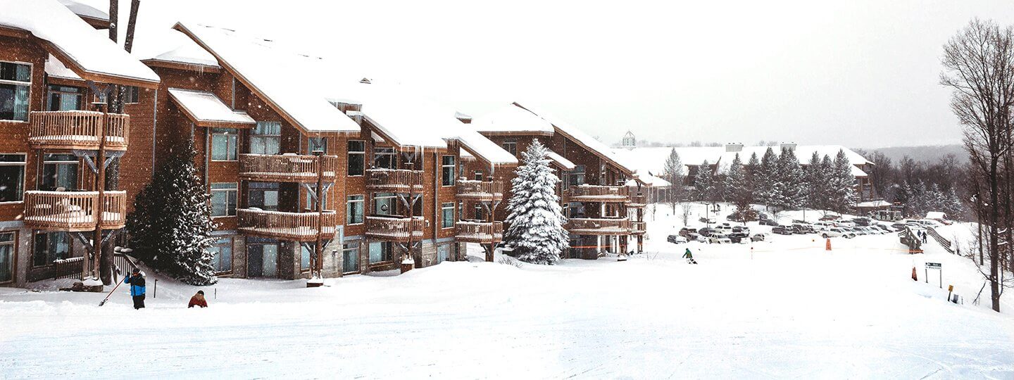 View of the snowy Summit Mountain at Shanty Creek Resorts in Michigan, showcasing a ski resort with a lodge and chalet against a beautiful winter backdrop.