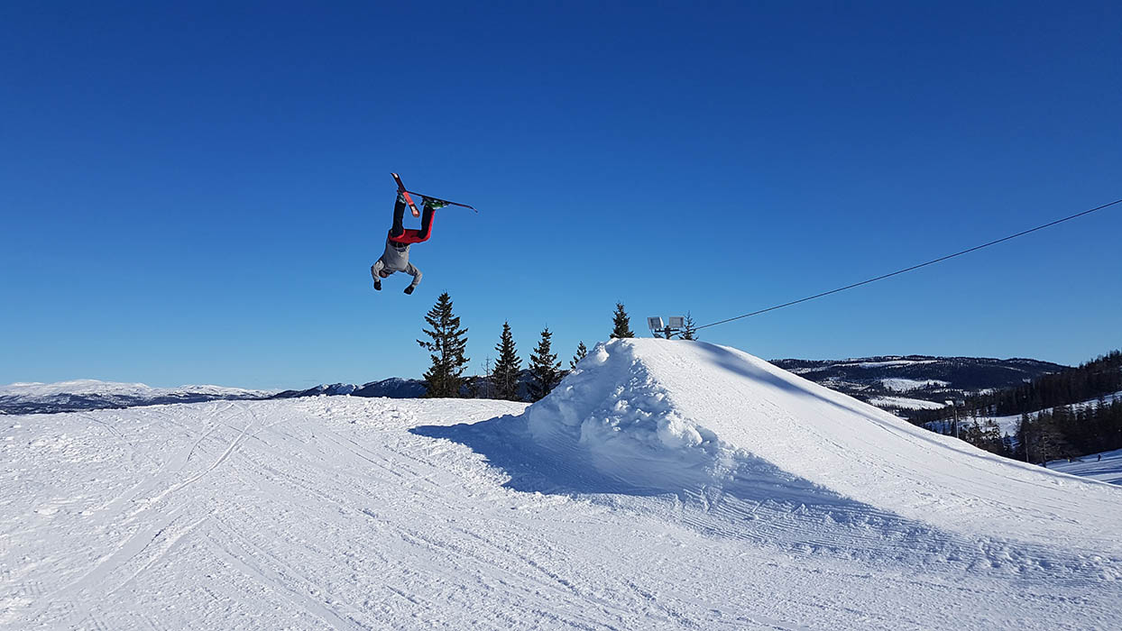 Grong in Norway - a man flying through the air while riding a snowboard.