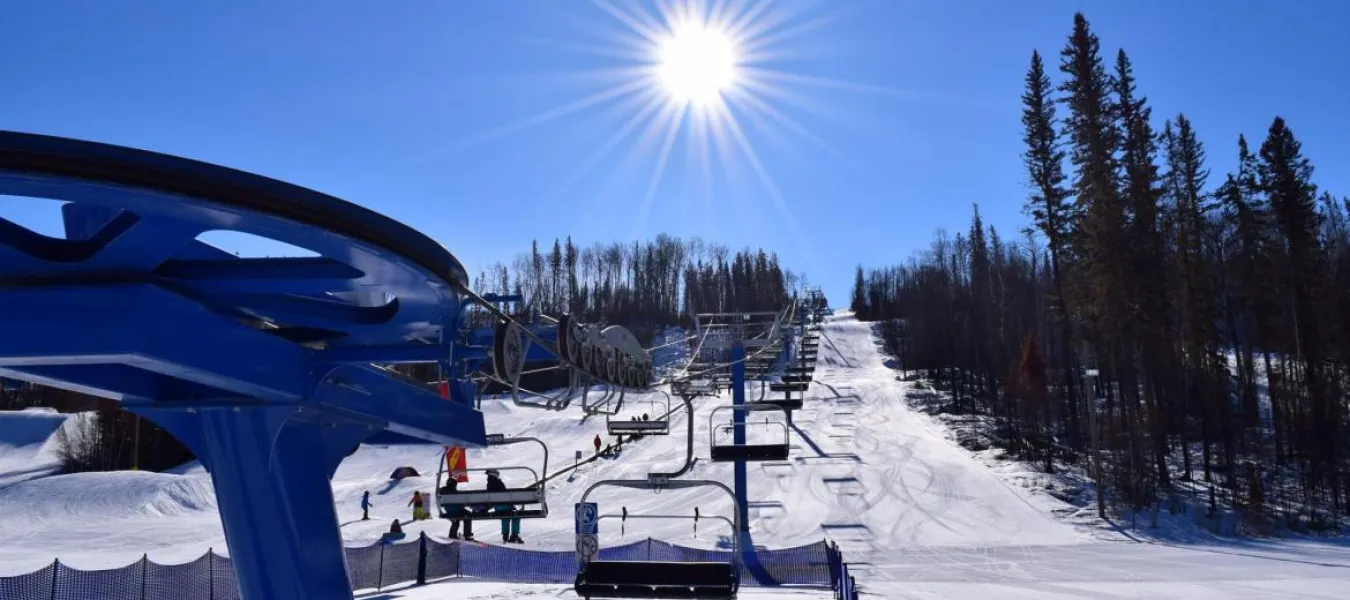 A scenic view of Vista Ridge ski resort in Northern Alberta Canada featuring a ski lift and a skier enjoying the winter sports scene.