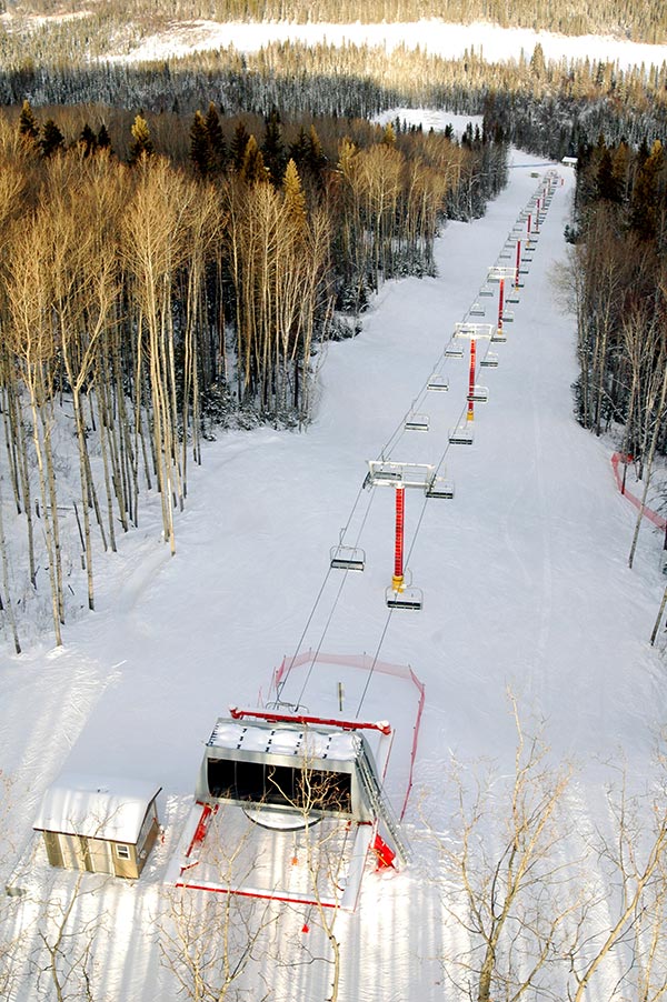A winter scene at Vista Ridge in Northern Alberta Canada featuring a ski lift situated in a ski resort with a skier enjoying the winter sports activities.