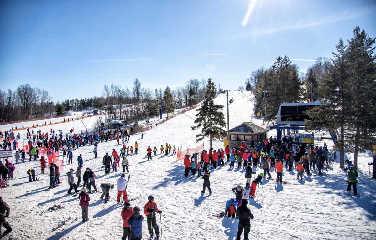 Chicopee in Canada - a large group of people skiing down a hill.
