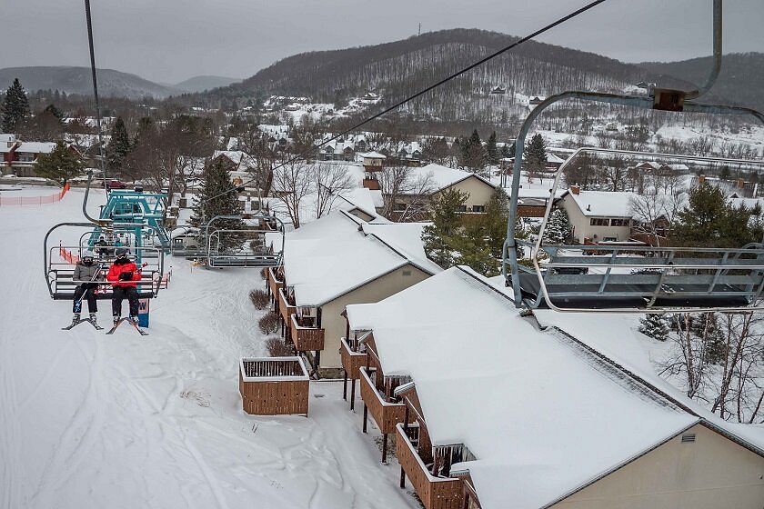 Winter scene at Holiday Mountain Ski Resort in The Catskills, New York. Skier gliding down the frosty slopes with ski lift in the background amidst stunning snowy scenery.