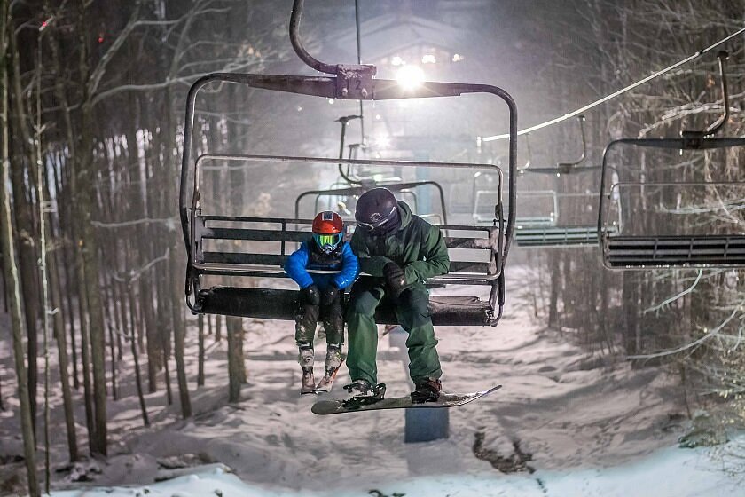 A ski lift ascends a mountain at Holiday Mountain Ski Resort in The Catskills NY USA. Numerous individuals are spotted engaging in winter sports activities with a family seen actively skiing.