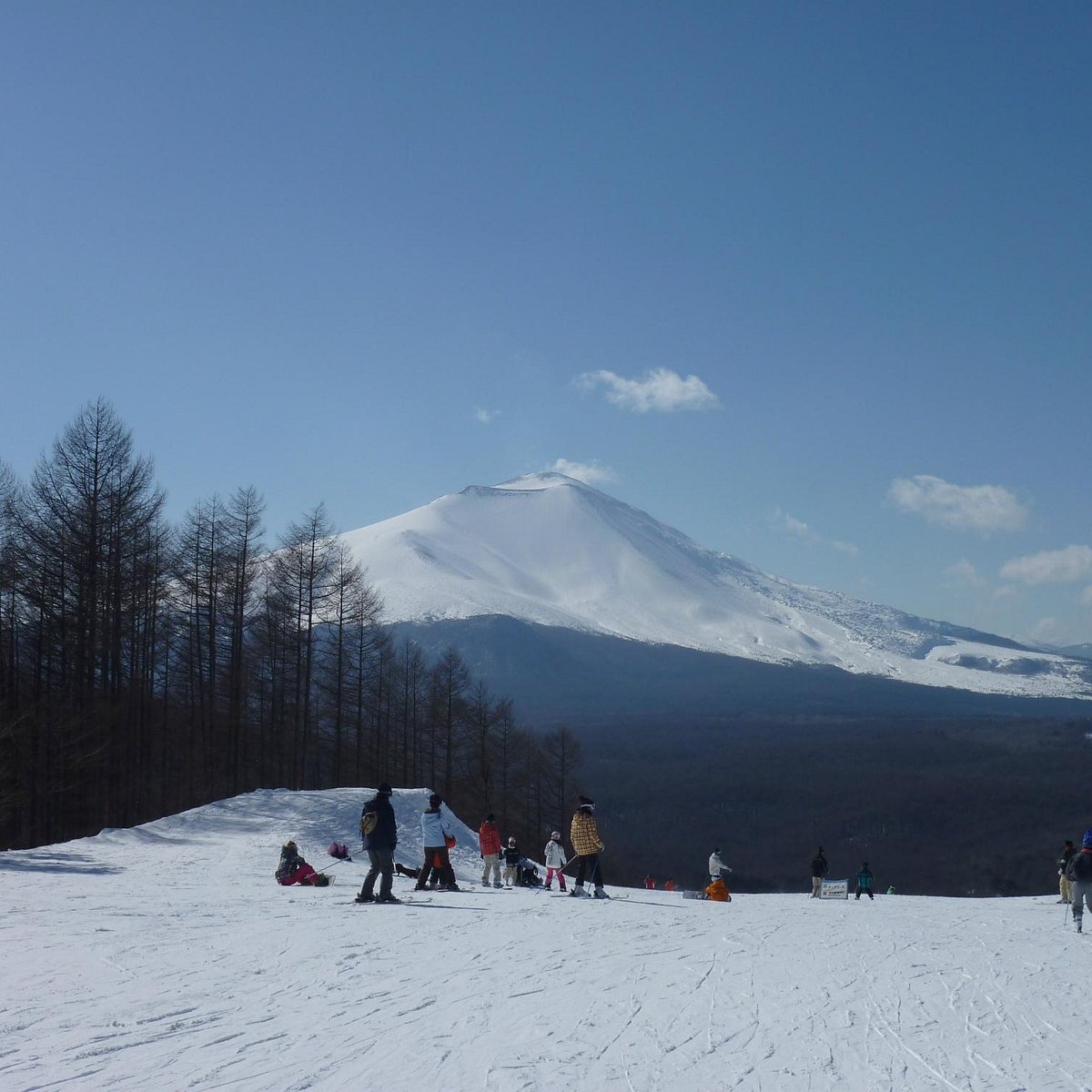Karuizawa Snow Park in Japan - a group of people skiing down a snow covered hill.