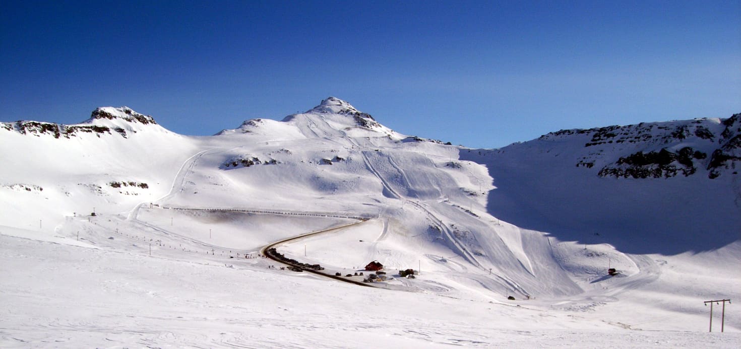 Oddsskarð in Iceland - a snow covered mountain with a ski lift going up it.