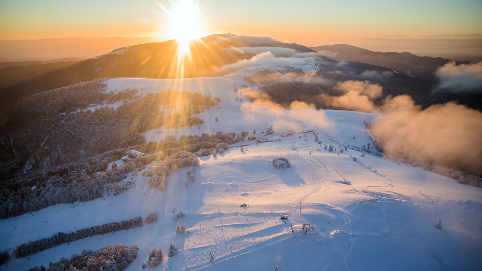 Le Markstein in France - the sun is shining over a snowy mountain.