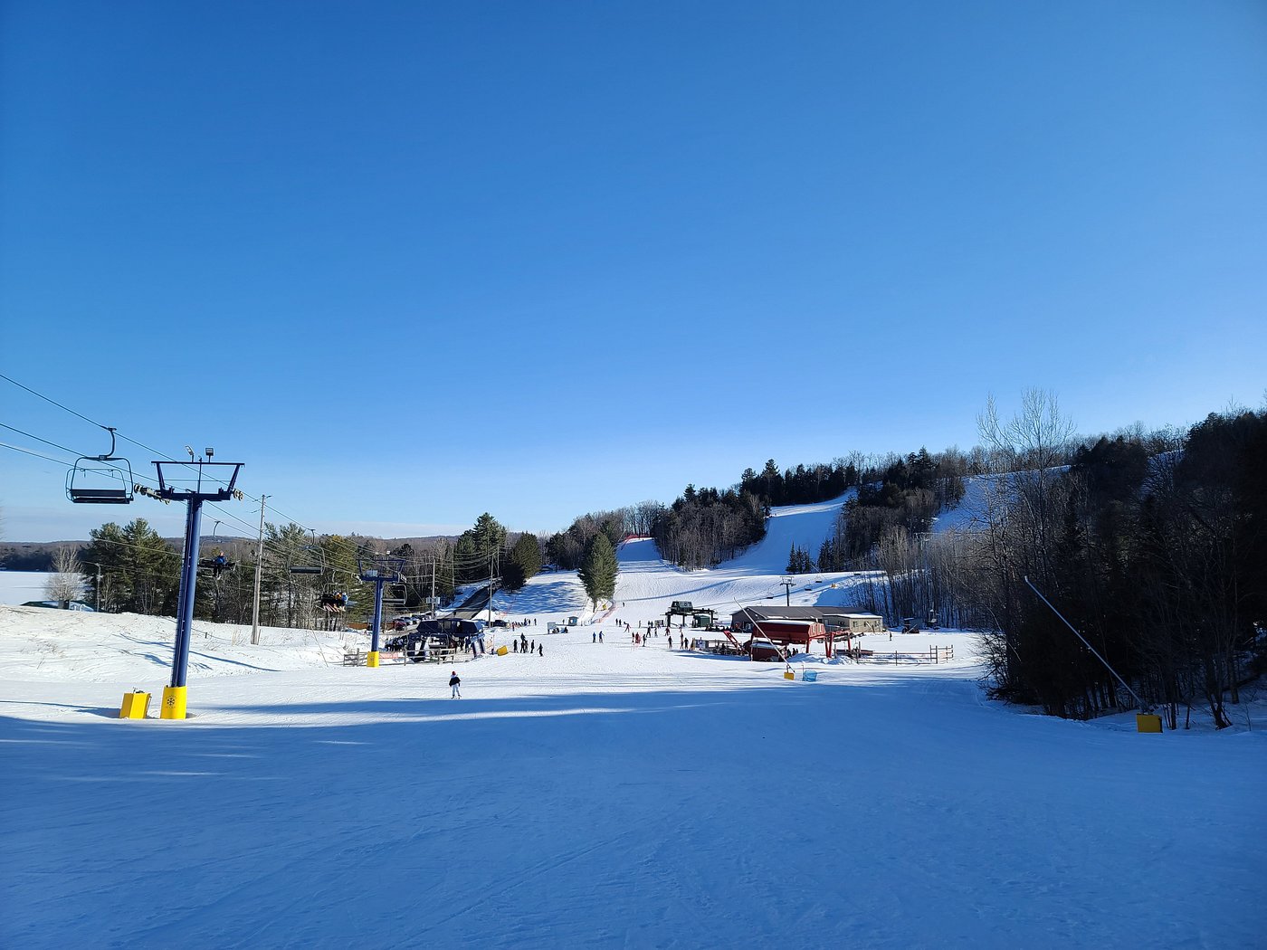 Winter sports scene at Hidden Valley Highlands in Northern Ontario, Canada, showcasing a bustling ski resort, skiing personnel on lift, enclosed by stunning winter scenery.