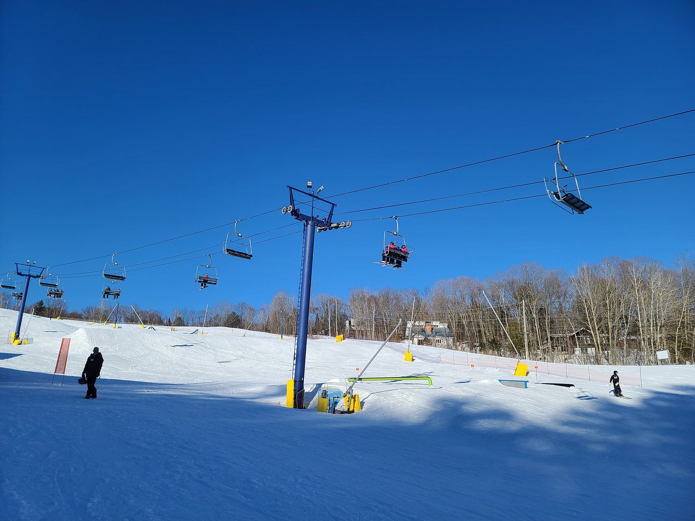 Winter scene at Hidden Valley Highlands in Northern Ontario, Canada, featuring skiers enjoying the slopes accessed by a ski lift, amidst a stunning snowy landscape of the ski resort.