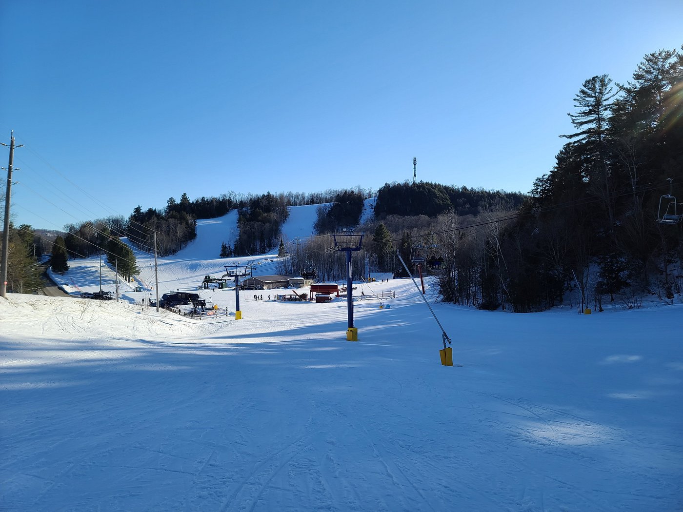 A winter sports scene at Hidden Valley Highlands in Northern Ontario Canada displaying a bustling ski resort replete with a ski lift and chalet.