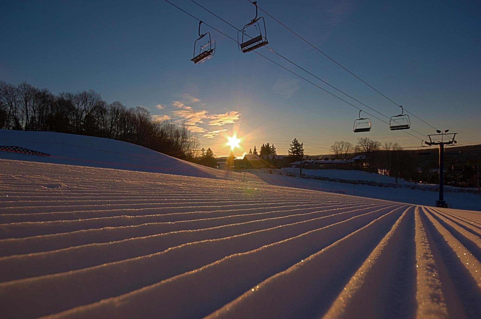 Skiers enjoying the snow-laden slopes at Hidden Valley Highlands Northern Ontario Canada with a ski lift providing access to the ski resort's challenging tracks.