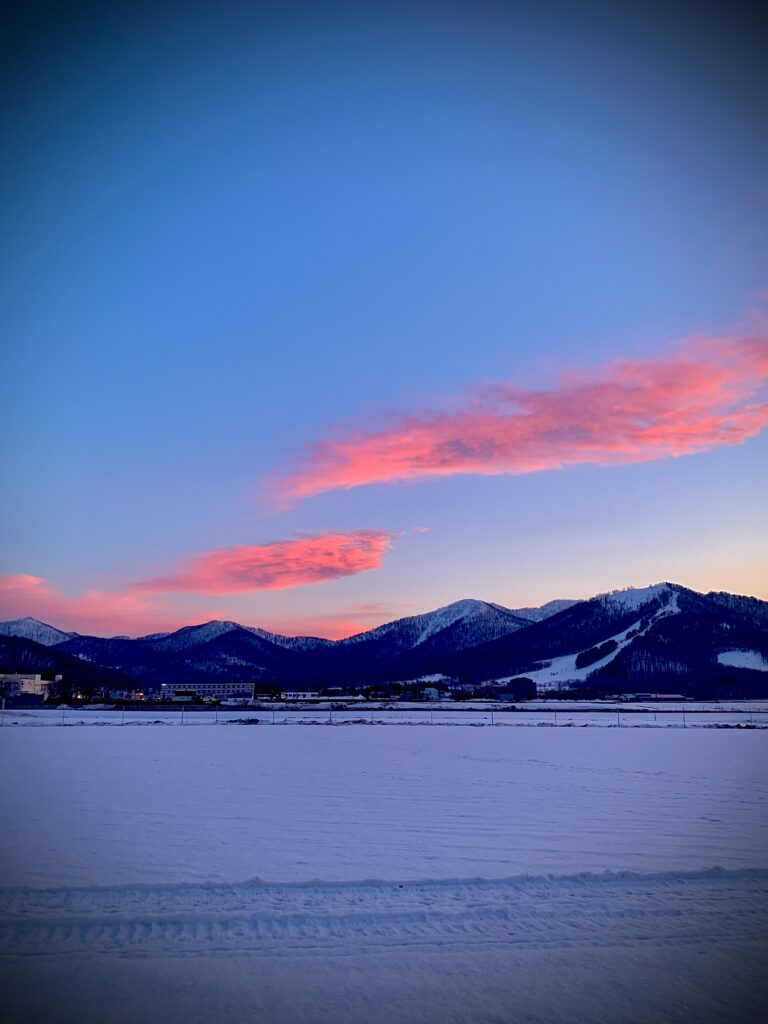 Minami Furano in Japan - the sun is setting over the mountains in the distance.