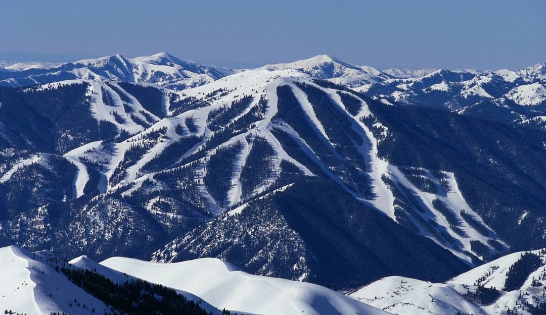 View of the snowy slopes at Bald Mountain ski resort Idaho with a hint of a mountain in the backdrop. The scene encapsulates the thrill of winter sports with a charming chalet completing the picture.
