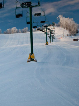 Mt Ashwabay – Salmo in USA - a man riding a snowboard down a snow covered slope.