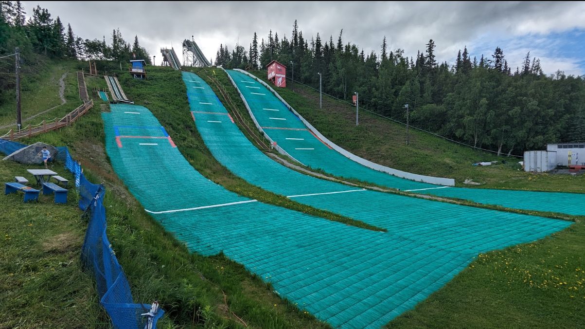 Hilltop – Anchorage in USA - a green slope covered in snow next to trees.