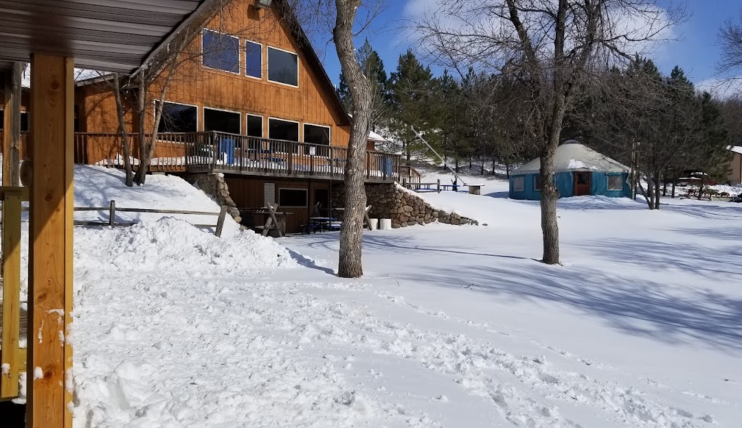 A bustling winter scene at Huff Hills in Mandan North Dakota featuring a buzzing ski resort a cozy lodge nestled amongst snowy landscapes and enthusiasts engaged in winter sports activities.