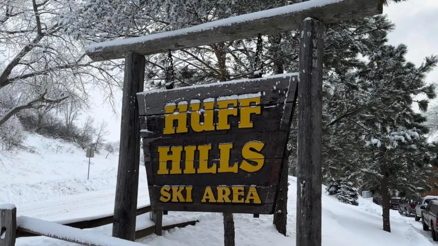 Ski resort at Huff Hills in Mandan, North Dakota, filled with winter sports activities. Skiers on the slope and ski lift are visible, all against a scenic snowy backdrop.