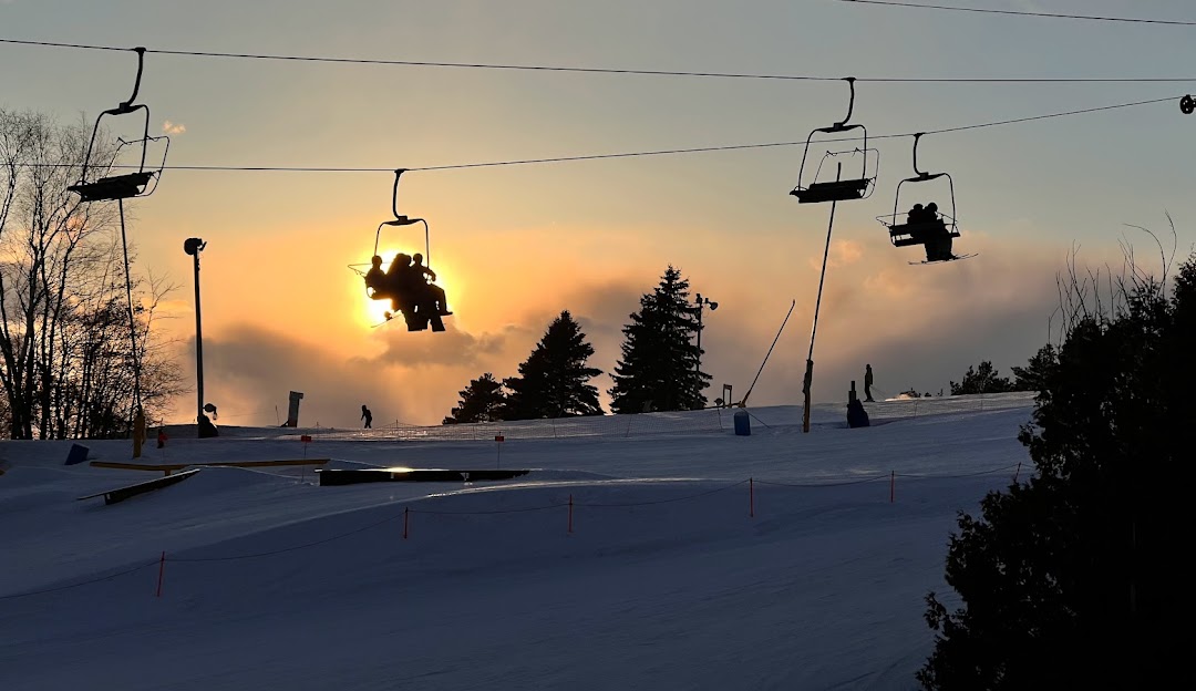 A bustling winter sports scene at Lakeridge Resort in Southern Ontario with skiers enjoying the slopes a ski lift in operation and a cozy chalet in the background.