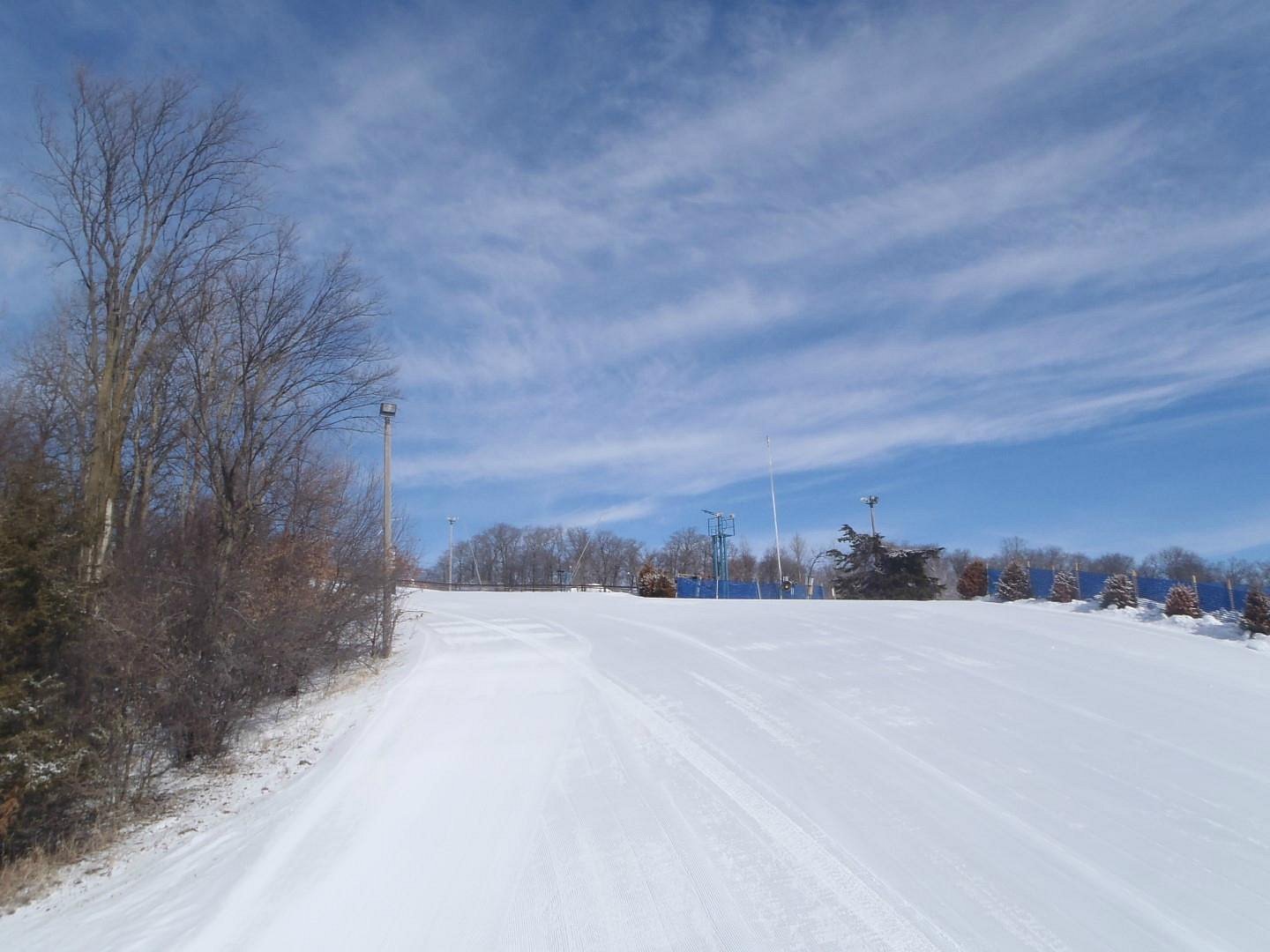 A winter sports scene at Powder Ridge Minnesota featuring picturesque winter scenery with snow-covered slopes. The winter sports centre and a chalet add charm to the landscape.